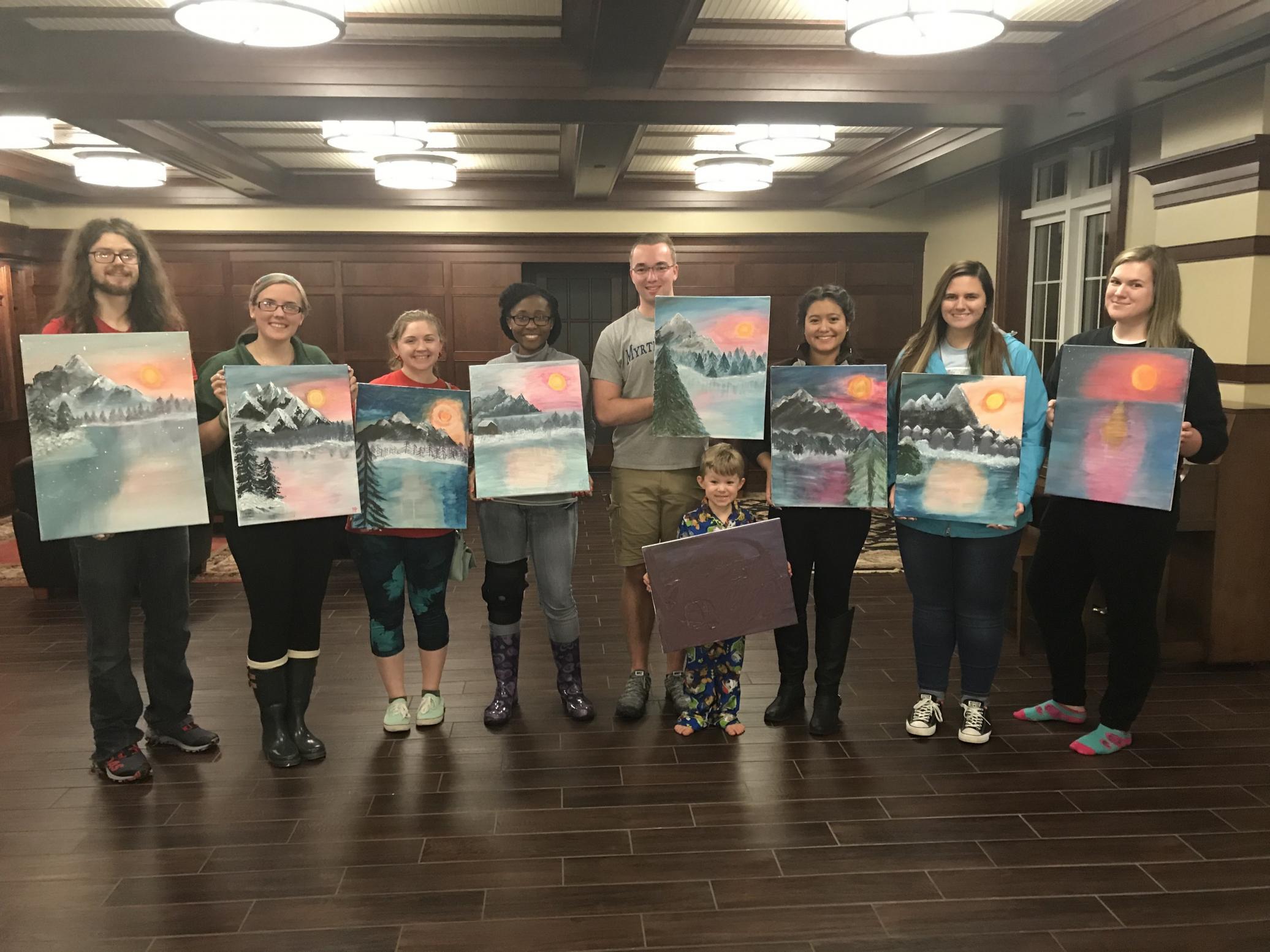 FRC members stand with finished paintings after art class